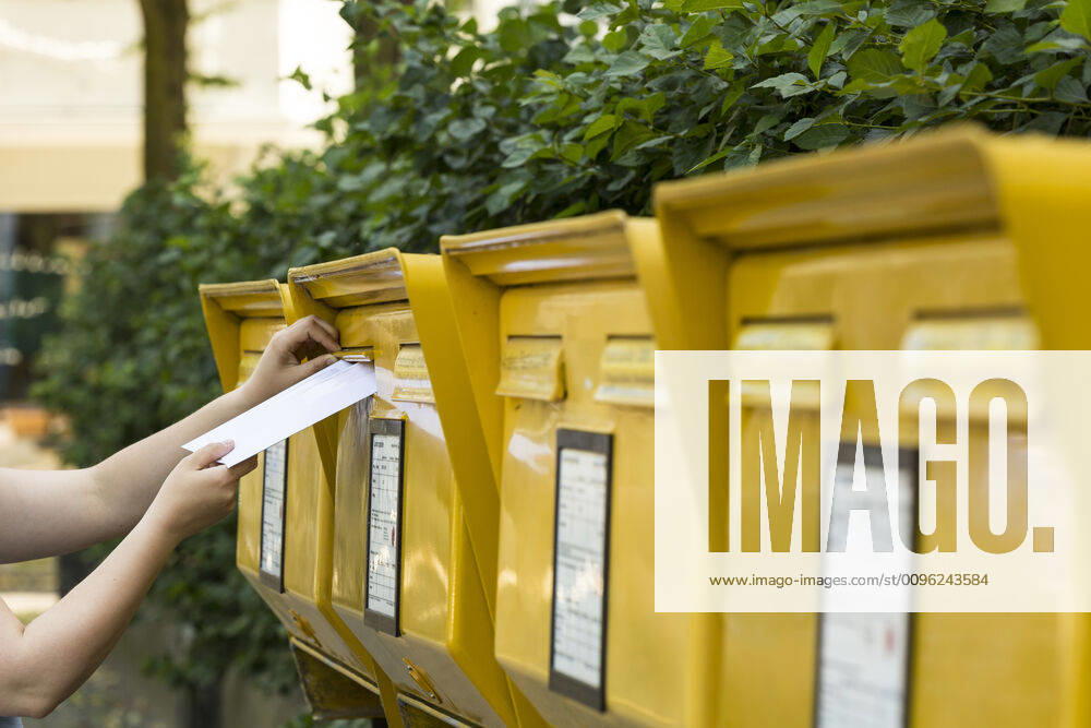 Frau steckt Brief in einen Briefkasten der Deutschen Post AG
