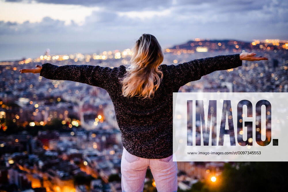 Young woman sitting on railing above the city using cell phone, Barcelona, Spain model released Symbolfoto GIOF07947