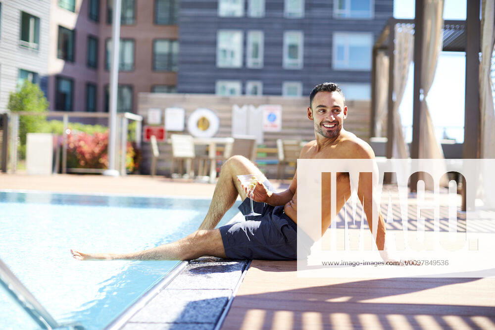 A man relaxes with a drink by the pool. Boston, MA, United States ,model released, Symbolfoto CR_SDXQ200115-197157-01