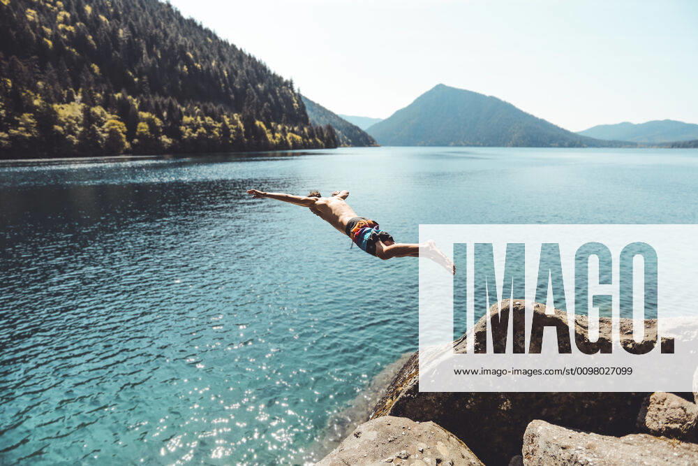 IMAGO Creative: Ende des Sommers Side view of young male jumping in alpine lake in front of mountains Port Angeles, WA, United States ,model released, Symbolfoto CR_MAKO200206D-304979-01