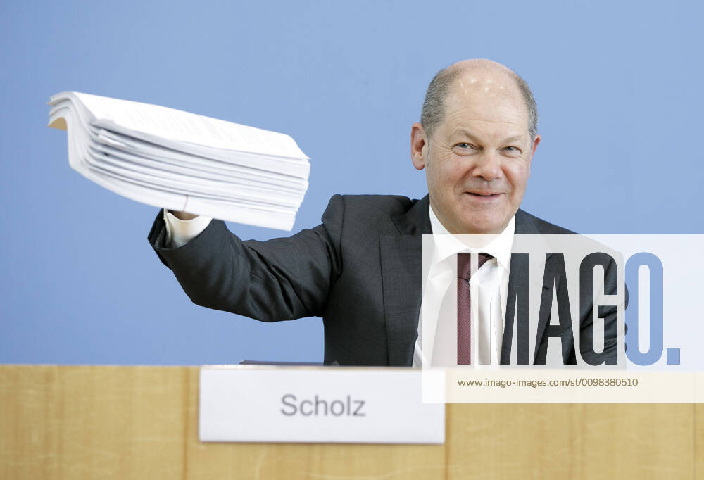 Bundesfinanzminister Olaf Scholz, SPD, spricht in der Bundespressekonferenz zum Nachtragshaushalt 2020 und die Reaktion auf die Corona-Krise. Hier haelt er einen Aktenstapel mit den neunen Gesetzen in die Kamera. Berlin, 23.03.2020 Berlin Deutschland