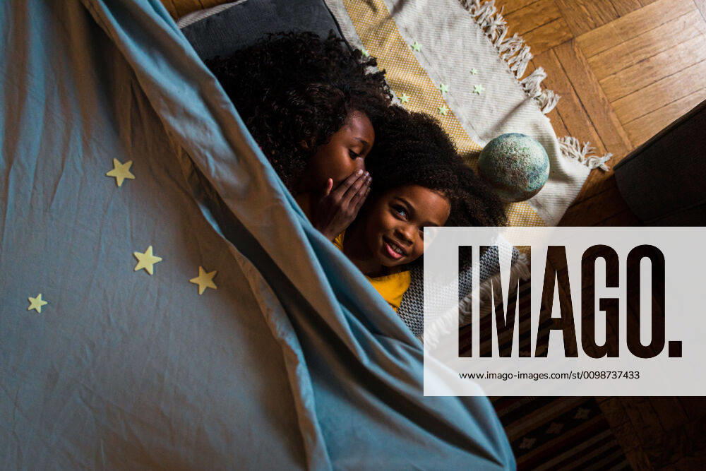 IMAGO Creative: Jahreszeit Winter, Fantasievoll drinnen spielen Overhead view of girl whispering with sister while relaxing at home New York, NY, United States ,model released, Symbolfoto ,property released CR_LIWEEE200227-318420-01