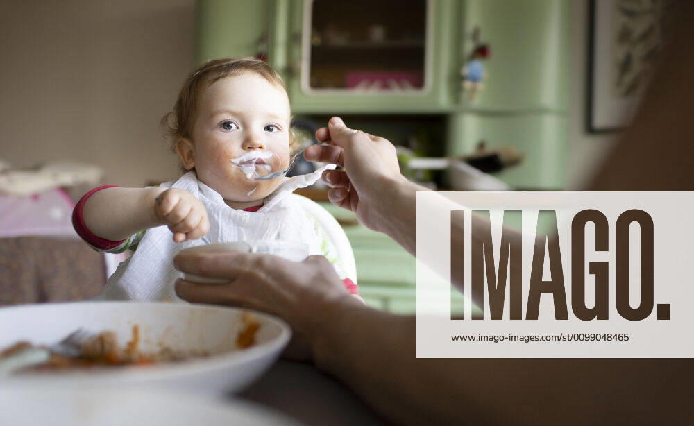 Portrait eines kleinen Jungen beim Essen, Bonn, 02.04.2020. Der Vater fuettert den Jungen mit einem Loeffel Joghurt. Bonn Deutschland
