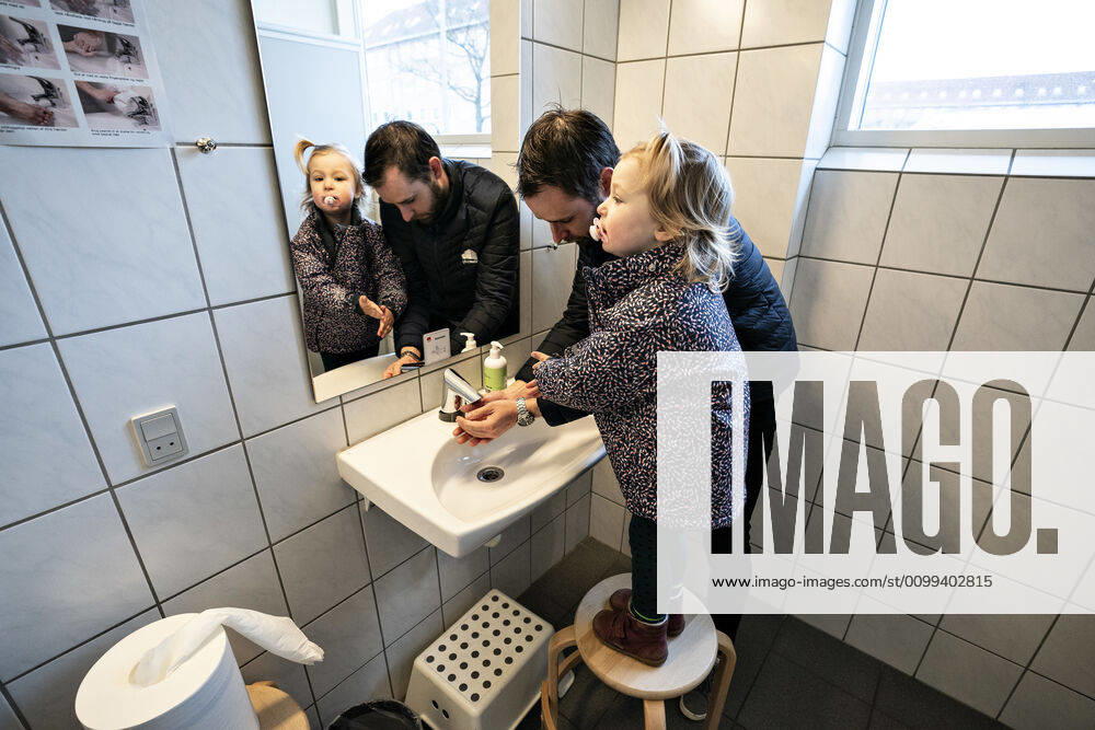 Vuggestuen DUI i Aalborg aabner igen for institutionens boern, onsdag morgen den 15. april 2020. Solvej vasker haender sammen med sin far. Paa grund af coronakrisen har vuggestuen vaeret lukket, og efter der er lavet om paa vuggestuen inden- og udendoers kan boernene og de voksne paedagoger holde afstand og vaske haender.. , Aalborg Jylland Denmark