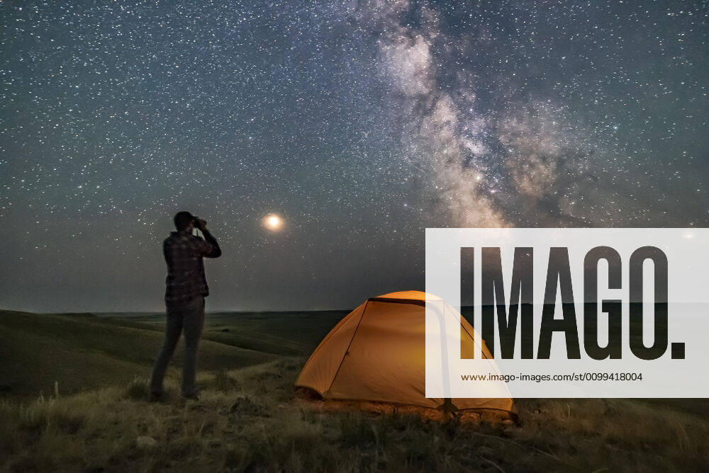 IMAGO Creative: Ende des Sommers A person poses for a scene in Grasslands National Park, Saskatchewan, Canada, of stargazing with binoculars under the Milky Way on a dark moonless night. Grasslands is perfect for stargazing as it is a Dark Sky Preserve and the horizon is vast and unobstructed. Mars is bright to the left and the galactic centre is to the south at right. The view is overlooking the Frenchman River Valley.