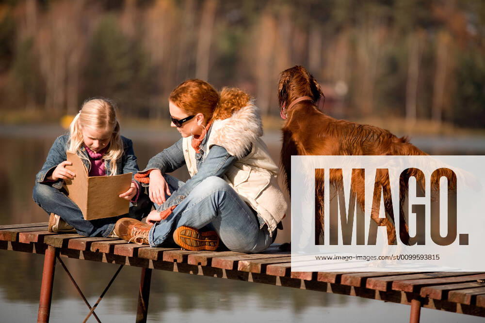 IMAGO Creative, Jahreszeit Herbst, Ferien IMAGO CREATIVE: Jahreszeit Herbst, Herbstanfang IMAGO CREATIVE: Jahreszeit Herbst, Herbstanfang autumn A girl reading a book with her mom at the lake in the forest, is a warm, sunny autumn day.