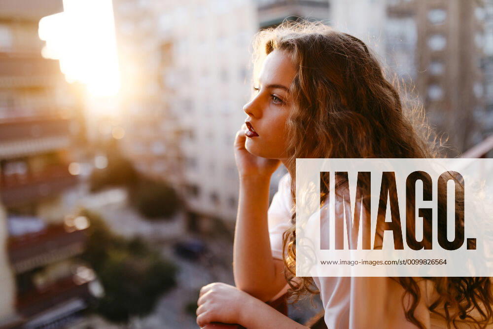 Portrait of beautiful young woman on balcony at sunset model released Symbolfoto TCEF00458