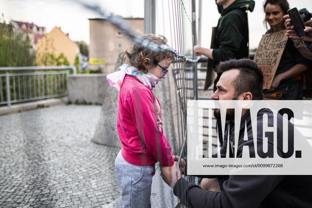 Ein Kind trifft auf sein Vater auf der gegenueberliegenden Seite der Grenze im Rahmen der Demonstration gegen die geschlossene Grenze zwischen Zgorzelec und Goerlitz, 24.04.2020. Zur Eindaemmung des Coronaviruses haben unter anderem Polen und Tschechien Mitte Maerz die Grenzen nach Deutschland geschlossen. Hintergrund des Protestes sind die aktuellen Einschraenkungen fuer Arbeiter, die normalerweise taeglich nach Deutschland pendeln, jetzt aber nach Wiedereinreise nach Polen in zweiwoechige Quarantaene muessten. Ausserdem sind grenzuebergreifende, familiaere Kontakte durch die geschlossenen Grenzen schwer moeglich. Goerlitz Deutschland