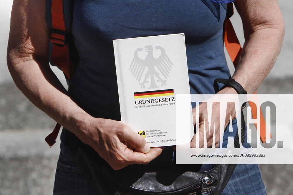 Eine genehmigte und auf wenige Teilnehmer begrenzte Demonstration gegen das coronabedingte Infektionsschutzgesetz und die damit einhergehenden Freiheitsbeschränkungen fand in der Innenstadt von Karlsruhe statt, Baden Württemberg, Deutschland: Frau hält eine Ausgabe des Grundgesetzes vor ihrem Körper.