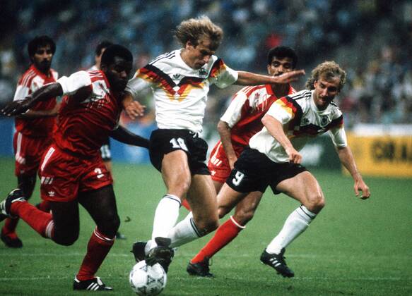 Jürgen Klinsmann (BR Deutschland, 2.v.li.) setzt sich gegen Khaleel Ghanim Mubarak (Vereinigte Arabische Emirate, li.) durch, daneben Rudi Völler (BR Deutschland, re.) und Hussain Hassan Mohamed (Vereinigte Arabische Emirate, 2.v.re.) Fußball WM Herren Weltmeisterschaft 1990, Nationalmannschaft, Nationalteam, Nationaltrikot, Länderspiel, Gruppe D Gruppe Mailand Dynamik, Kampf,