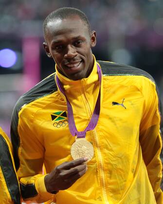 Jamaica s Usain Bolt rholds his Goldmedal at the medal ceremony for the 100m at the London 2012 Summer Olympics on August 6, 2012 in London.  OLY20120806630