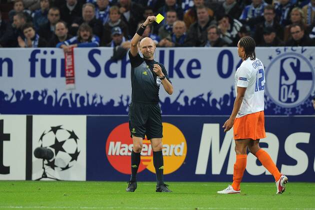 Fußball Champions League Schalke 04 - HSC Montpellier am 03.10.2012 in der Veltins-Arena in Gelsenkirchen FIFA-Schiedsrichter Sergey Karasev ( Russland ), links - zeigt Daniel Congre ( Montpellier ), rechts die gelbe Karte
