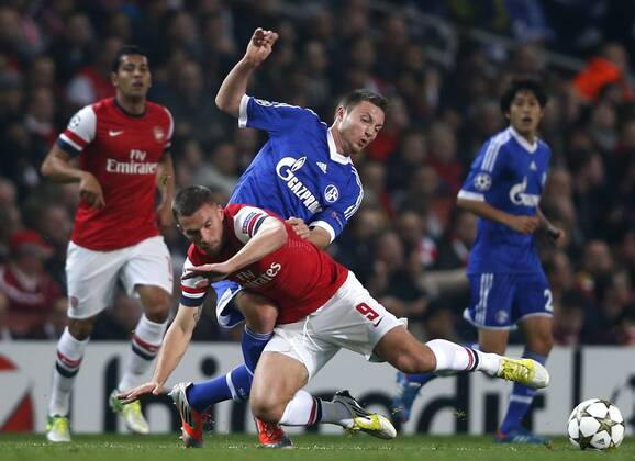 (121025) -- LONDON, Oct. 25, 2012(Xinhua) -- Lukas Podolski (Bottom) of Arsenal vies with Marco Hoger of Schalke 04 during the UEFA Champions League Group B match between Arsenal and FC Schalke 04 at the Emirates Stadium in London, Britain on October 24, 2012. FC Schalke 04 won 2-0. (Xinhua Wang Lili) BRITAIN-LONDON-SOCCER-UEFA-CHAMPIONS LEAGUE-ARSENAL-SCHALKE 