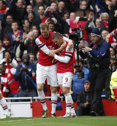 Arsenal s Per Mertesacker celebrates with goalscorer Lukas Podolski ..Arsenal FC London v Tottenham Hotspur - Premier League- Emirates Stadium, London- 17 11 12 - EDITORIAL USE ONLY. No use with unauthorised audio, video, data, fixture lists, club league logos or live services. Online in-match use limited to 120 images, no video emulation. No use in betting, games or single club league player publications.