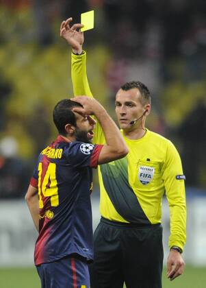 ITAR-TASS: MOSCOW, RUSSIA. NOVEMBER 20, 2012. Croatian football referee Ivan Bebek (R) shows a yellow card to Barcelona s Javier Mascherano during a UEFA Champions Legaue Group G Round 5 football match against Spartak Moscow at Luzhniki Stadium. FC Barcelona won the game 3:0.  premiumd RE10DECB