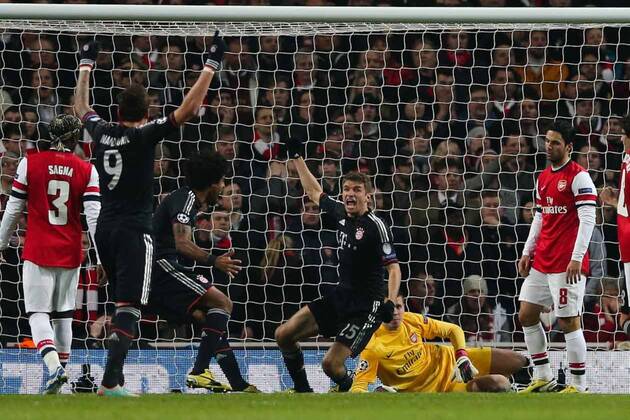 Football - 2012 2013 Champions League - Round of 16, First Leg: Arsenal vs. Bayern Munich Bayern Munich s Thomas Müller celebrates scoring while a dejected Mikel Arteta of Arsenal (right) looks on at the Emirates Stadium, London 
