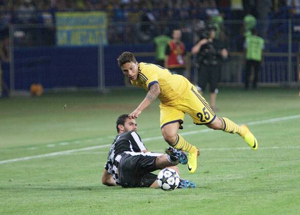 FC Metalist Kharkiv midfielder Romero Marlos (yellow kit) trips over his PAOK FC opponent during the UEFA Champions League third qualifying round second leg fixture at Metalist Stadium, Kharkiv, northeastern Ukraine, August 7, 2013. UKRINFORM. 