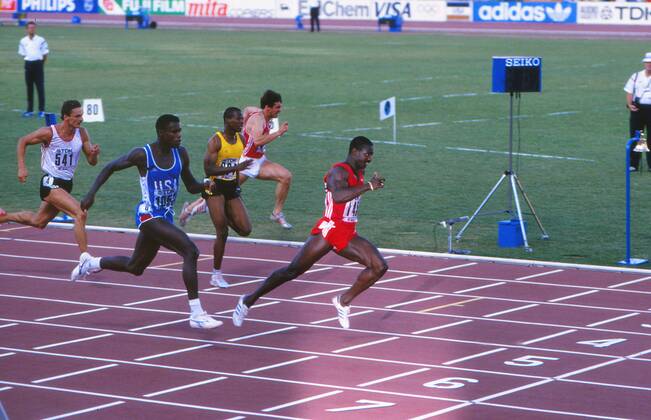 Athletics - 1987 IAAF Rome World Championships - Men s 100m Final Canada s Ben Johnson (red) shocks the world by defeating the USA s Carl Lewis (in blue) to win the race in a new World Record of 9.83s at the Stadio Olimpico. Jamaica s Raymond Stewart (yellow) is also pictured. 30 08 1987 