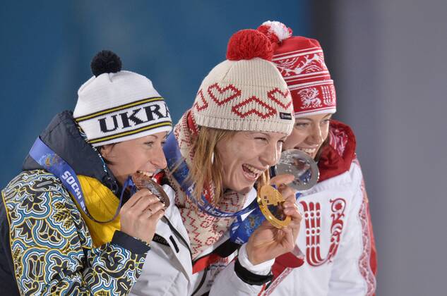 Russia s Olga Vilukhina (R-L), Slovokia s Anastasiya Kuzmina, and Ukraine s Vita Semerenko bite their bronze, gold and silver during their victory ceremony for the Biathalon Women s Sprint at the Sochi 2014 Winter Olympics on February 10, 2014 in Sochi, Russia.  OLY20140210136