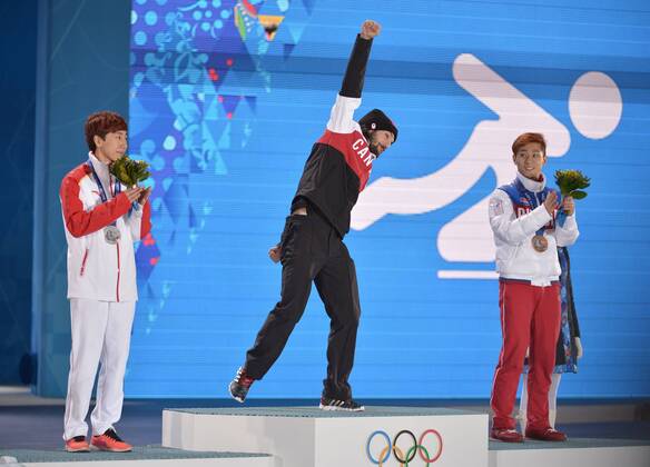 Canada s Charles Hamelin (C) celebrates before he is awarded the gold medal as China s Han Tianyu (L), who won silver and Russia s Victor An, who won bronze, stand with him during the victory ceremony for the men s 1500M short track speed skating at the Sochi 2014 Winter Olympics on February 10, 2014 in Sochi, Russia.  OLY20140210168