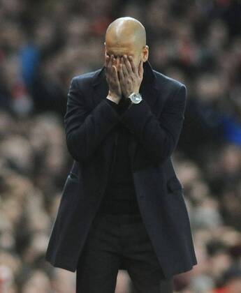 Football - 2013 2014 Champions League - Round of 16, First Leg: Arsenal vs. Bayern Munich Bayern s manager Josep Guardiola covers his hans over his face after their penalty miss at The Emirates. COLORSPORT ANDREW COWIE 