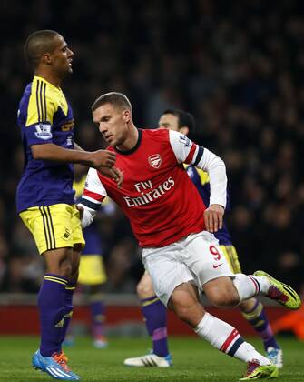 Lukas Podolski (R) of Arsenal reacts after scoring during the Barclays Premier League match between Arsenal and Swansea City at Emirates Stadium in London, Britain on Mar. 25, 2014. The match ended with a 2-2 draw. (Xinhua Wang Lili) FOR EDITORIAL USE ONLY. NOT FOR SALE FOR MARKETING OR ADVERTISING CAMPAIGNS. NO USE WITH UNAUTHORIZED AUDIO, VIDEO, DATA, FIXTURE LISTS, CLUB LEAGUE LOGOS OR LIVE SERVICES. ONLINE IN-MATCH USE LIMITED TO 45 IMAGES, NO VIDEO EMULATION. NO USE IN BETTING, GAMES OR SINGLE CLUB LEAGUE PLAYER PUBLICATIONS. (SP)BRITAIN-LONDON-SOCCER-PREMIER LEAGUE-ARSENAL VS SWANSEA CITY 