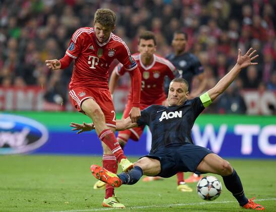FUSSBALL CHAMPIONS LEAGUE VIERTELFINALE SAISON 2013 2014 FC Bayern München - Manchester United FC 09.04.2014 Thomas Müller (FC Bayern München) erzielt das Tor zum 2:1. Nemanja Vidic (re, Manchester United FC) kommt nicht mehr an den k 