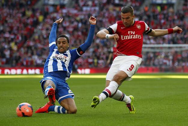 Lukas Podolski of Arsenal vies with James Perch of Wigan Athletic during FA Cup semifinal match between Arsenal and Wigan Athletic at Wembley Stadium in London, Britain, on April 12, 2014. Arsenal advanced to the final with winning 4-2 on penalties after a 1-1 draw. (Xinhua Wang Lili) FOR EDITORIAL USE ONLY. NOT FOR SALE FOR MARKETING OR ADVERTISING CAMPAIGNS. NO USE WITH UNAUTHORIZED AUDIO, VIDEO, DATA, FIXTURE LISTS, CLUBLEAGUE LOGOS OR LIVE SERVICES. ONLINE IN-MATCH USE LIMITED TO 45 IMAGES, NO VIDEO EMULATION. NO USE IN BETTING, GAMES OR SINGLE CLUBLEAGUEPLAYER PUBLICATIONS. (SP)BRITAIN-LONDON-SOCCER-FA CUP-ARSENAL VS WIGAN 