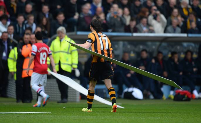 Santi Cazorla of Arsenal and Geroge Boyd of Hull City carries off advertising hoardings after a gust of wind blew them onto the pitch - Barclays Premier League - Hull City v Arsenal - KC Stadium - Hull - England - 20th April 2014 - Pic Simon Bellis Sportimage EDITORIAL USE ONLY. No use with unauthorised audio, video, data, fixture lists, club league logos or live services. Online in-match use limited to 120 images, no video emulation. No use in betting, games or single club league player publications.