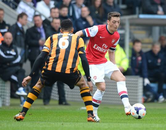 Mesut Ozil of Arsenal played the ball past Curtis Davies of Hull City - Barclays Premier League - Hull City v Arsenal - KC Stadium - Hull - England - 20th April 2014 - Pic Simon Bellis Sportimage EDITORIAL USE ONLY. No use with unauthorised audio, video, data, fixture lists, club league logos or live services. Online in-match use limited to 120 images, no video emulation. No use in betting, games or single club league player publications.