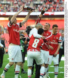 Football - 2014 FA Cup Final - Arsenal. Arsenal manager Arsene Wenger is showered with Champagne by Per Mertesacker and Lukas Podolski, right: Mesut Özil - at Wembley. COLORSPORT ANDREW COWIE 