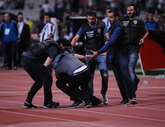 UEFA Champions League playoff first leg match match between Besiktas and Arsenal at Olympic stadium in istanbul 19 august 2014. Score: Besiktas 0 - Arsenal 0 Pictured: Turkish police officer checks a fan of Besiktas who jumped onto the field during the UEFA Champions League play-off first leg football match Besiktas vs Arsenal at the Ataturk Olympic Stadium in Istanbul, on August 19, 2014. 