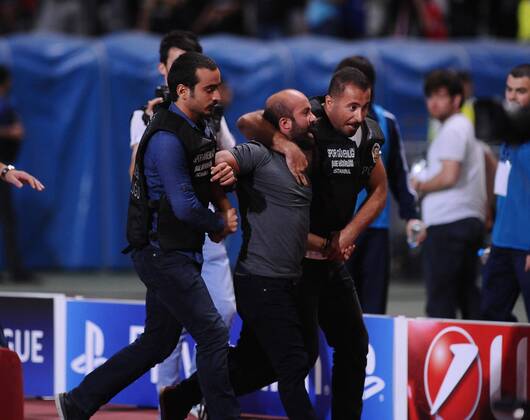 UEFA Champions League playoff first leg match match between Besiktas and Arsenal at Olympic stadium in istanbul 19 august 2014. Score: Besiktas 0 - Arsenal 0 Pictured: Turkish police officer checks a fan of Besiktas who jumped onto the field during the UEFA Champions League play-off first leg football match Besiktas vs Arsenal at the Ataturk Olympic Stadium in Istanbul, on August 19, 2014. 