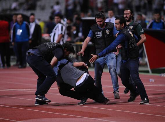 UEFA Champions League playoff first leg match match between Besiktas and Arsenal at Olympic stadium in istanbul 19 august 2014. Score: Besiktas 0 - Arsenal 0 Pictured: Turkish police officer checks a fan of Besiktas who jumped onto the field during the UEFA Champions League play-off first leg football match Besiktas vs Arsenal at the Ataturk Olympic Stadium in Istanbul, on August 19, 2014.