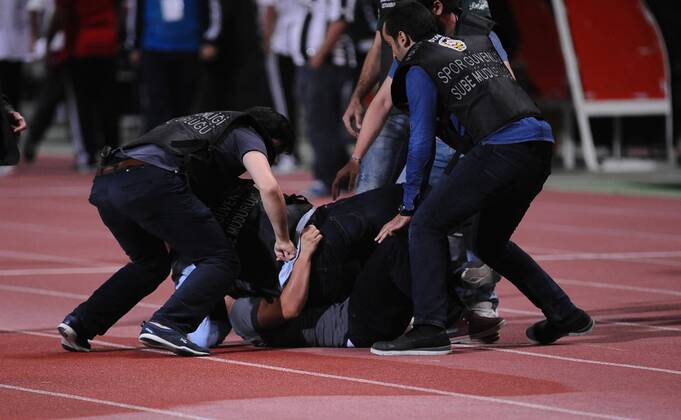 UEFA Champions League playoff first leg match match between Besiktas and Arsenal at Olympic stadium in istanbul 19 august 2014. Score: Besiktas 0 - Arsenal 0 Pictured: Turkish police officer checks a fan of Besiktas who jumped onto the field during the UEFA Champions League play-off first leg football match Besiktas vs Arsenal at the Ataturk Olympic Stadium in Istanbul, on August 19, 2014.