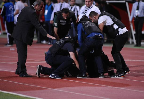 UEFA Champions League playoff first leg match match between Besiktas and Arsenal at Olympic stadium in istanbul 19 august 2014. Score: Besiktas 0 - Arsenal 0 Pictured: Turkish police officer checks a fan of Besiktas who jumped onto the field during the UEFA Champions League play-off first leg football match Besiktas vs Arsenal at the Ataturk Olympic Stadium in Istanbul, on August 19, 2014.