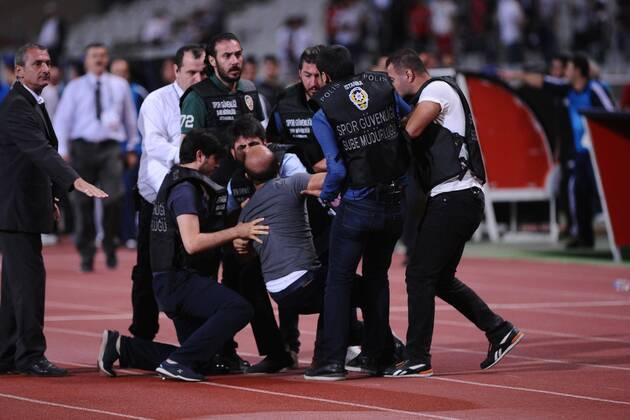 UEFA Champions League playoff first leg match match between Besiktas and Arsenal at Olympic stadium in istanbul 19 august 2014. Score: Besiktas 0 - Arsenal 0 Pictured: Turkish police officer checks a fan of Besiktas who jumped onto the field during the UEFA Champions League play-off first leg football match Besiktas vs Arsenal at the Ataturk Olympic Stadium in Istanbul, on August 19, 2014.
