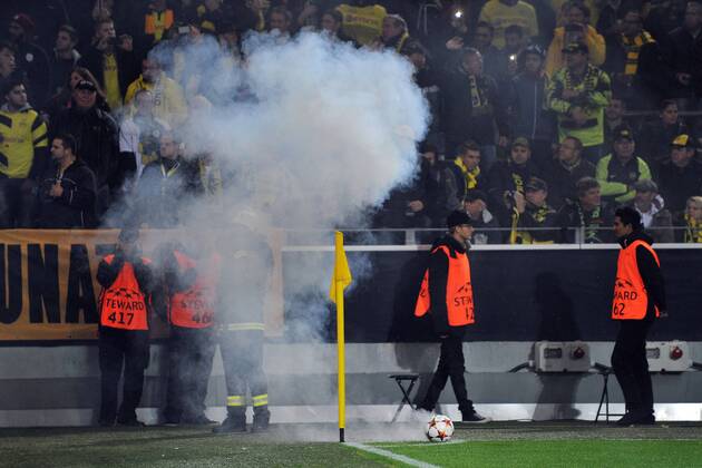 Aktuell Fussball, Champions League, Spielunterbrechung bei Borussia Dortmund - Galatasaray Istanbul Borussia Dortmund vs. Galatasaray Istanbul --- Fussball --- Champions League --- 04.11.2014 Rauch, Nebel, Feuer an der Eckfahne vor dem Galatasaray-Block, davor ein Fussball mit dem Logo der Champions League, ein Feuerwehrmann und Ordner, Sicherheit, Krawall, Unruhe, Ausschreitungen, Pyrotechnik, Pyros, Bengalisches Feuer, Bengalos, Fans, Anhänger, Anhaenger, Zuschauer,