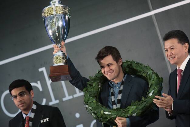 SOCHI, RUSSIA.NOVEMBER 25, 2014. Indian chess player Viswanathan (Vishy) Anand, left, and Kirsan Ilyumzhinov, the president of the World Chess Federation (FIDE), right, look on as chess champion Magnus Carlsen (C) of Norway holds up his trophy after winning the FIDE World Chess Championship 2014.  premiumd RE155C9A