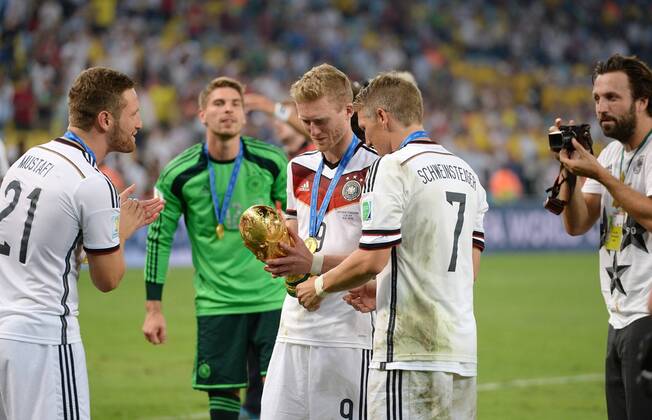 FUSSBALL WM 2014 FINALE Deutschland - Argentinien 13.07.2014 DEUTSCHLAND FEIERT DEN WM TITEL 2014: Andre Schürrle (Mitte li) und Bastian Schweinsteiger (Mitte re) WM Pokal fotografiert von Paul Ripke (re) beobachtet von Shkodran Mustafi (li)