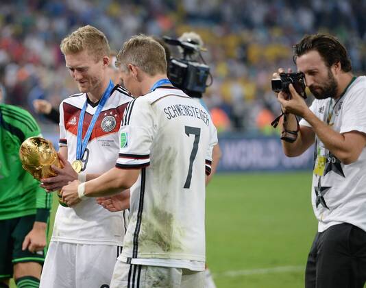 FUSSBALL WM 2014 FINALE Deutschland - Argentinien 13.07.2014 DEUTSCHLAND FEIERT DEN WM TITEL 2014: Andre Schürrle (li) und Bastian Schweinsteiger (Mitte) mit WM Pokal fotografiert von Paul Ripke (re)