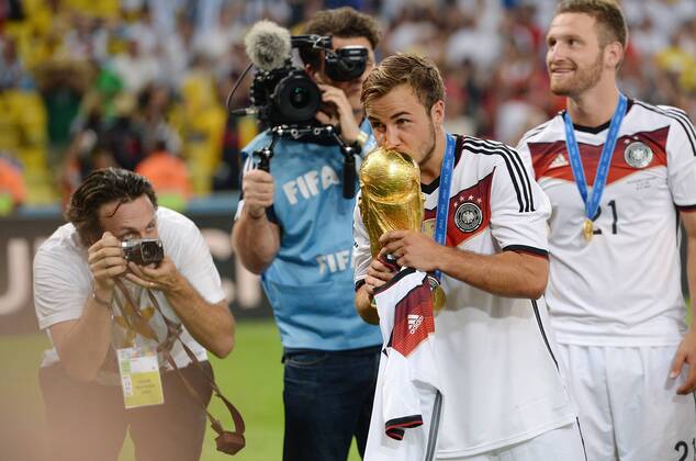 FUSSBALL WM 2014 FINALE Deutschland - Argentinien 13.07.2014 DEUTSCHLAND FEIERT DEN WM TITEL 2014: Matchwinner, Torschütze zum 1-0 Sieg, Mario Götze (Mitte) küsst den WM Pokal fotografiert von Paul Ripke (li); Shkodran Mustafi (re hinten)