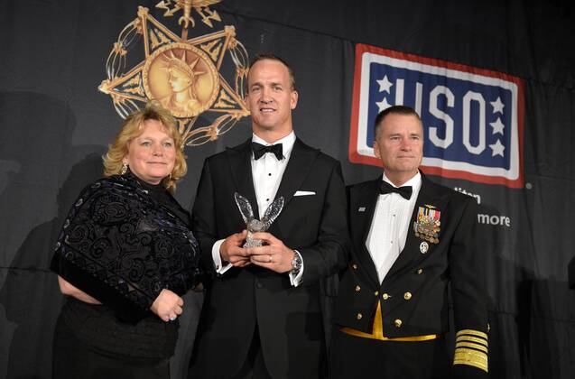 Denver Broncos quarterback Peyton Manning (C) accepts the USO-Metro Merit Award from Vice Chairman of the Joint Chiefs of Staff Admiral James Winnefeld (R) and Winnefeld s wife Mary, at the USO of Metropolitan Washington-Baltimore annual gala, March 24, 2015. Manning was honored for time he has spent touring and visiting military service members around the world. HO USO  WAP20150324502 MIKExTHEILER