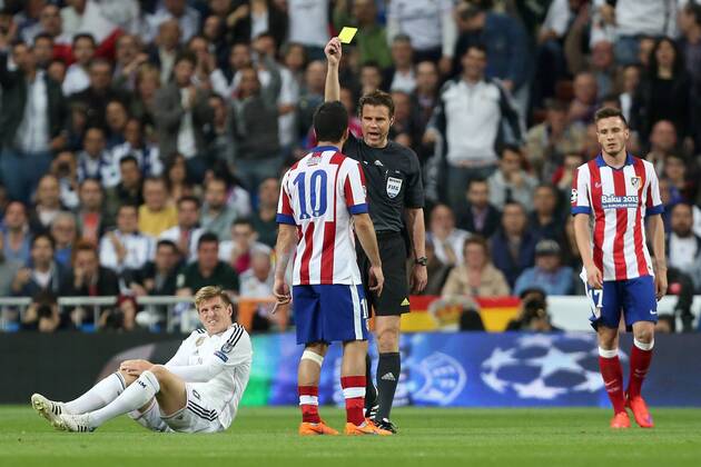 Arda Turan of Atletico is shown a yellow card for his challenge on Toni Kroos of Real Madrid - Real Madrid vs. Atletico Madrid - UEFA Champions League - Quarter Final Second Leg - Santiago Bernabeu - Madrid - 22 04 2015 EDITORIAL USE ONLY. No use with unauthorised audio, video, data, fixture lists, club league logos or live services. Online in-match use limited to 120 images, no video emulation. No use in betting, games or single club league player publications.
