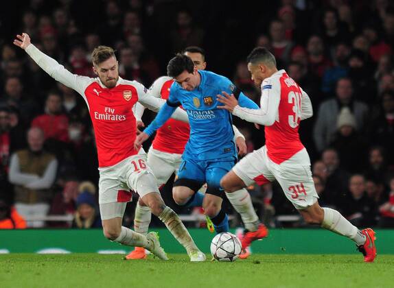 Football - 2015 2016 Champions League - Round of 16, First Leg: Arsenal vs. Barcelona Lionel Messi of Barcelona is challenged by Aaron Ramsey and Francis Coquelin at The Emirates. COLORSPORT ANDREW COWIE