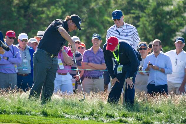 Phil Mickelson confers with a USGA official near the 12th green in the first round of the 118th U.S. Open Championship at Shinnecock Hills Golf Club in Southampton, New York on June 14, 2018.  NYP20180614133 COREYxSIPKIN