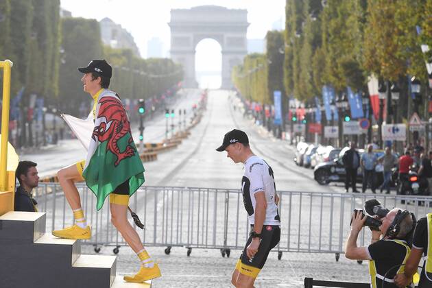 Overall winner British Geraint Thomas of Team Sky, carrying a Welsh flag and British Chris Froome of Team Sky mount the steps up to the podium with a view on the Arc de Triomphe, on the Champs Elysees, after the last stage of the 105th edition of the Tour de France cycling race, 116km from Houilles to Paris, France, Sunday 29 July 2018. This year s Tour de France takes place from July 7th to July 29th. DAVIDxSTOCKMAN  x05395072x