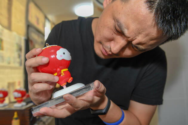 (190926) -- CHANGCHUN, Sept. 26, 2019 -- Designer Xu Guojun fastens a mascot model at Jilin University of Arts in Changchun, northeast China s Jilin Province on Sept. 26, 2019. Shuey Rhon Rhon, the mascot of the 2022 Paralympic Winter games, Winterspiele,Spiele, Summer games is a Chinese lantern child ready to welcome friends from around the world for a big party. Exuding positivity, the glow emanating from its heart symbolises the inspiring warmth, friendship, courage and perseverance of Para athletes that light up the dreams of millions every day. ) (SP)JILIN-CHANGCHUN-2022 PARALYMPIC WINTER GAMES-MASCOT ZhangxNan