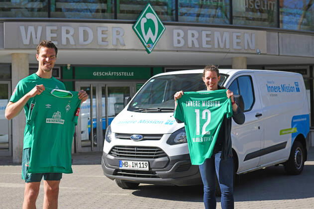 Bilder des Jahres 2020, Sport 04 April Sport Themen der Woche KW15 Sport Bilder des Tages STAYATHOME-TRIKOT: WERDER SPENDET 20.000 EURO FÜR INNERE MISSION 09.04.2020, Trainingsgelaende am wohninvest WESERSTADION,, Bremen, STAYATHOME-TRIKOT: WERDER SPENDET 20.000 EURO FÜR INNERE MISSION, Das STAYATHOMETRIKOT ist der Verkaufsschlager in Werders Online-Shop. Die Grün-Weißen und ihr Hauptsponsor WIESENHOF haben das Sondertrikot mit der Botschaft, die Menschenleben rettet, in den Verkauf gegeben und dürfen sich über einen riesigen Ansturm freuen. Einer der großen Gewinner der Aktion ist der Verein für Innere Mission in Bremen. Fünf Euro spendet Werder Bremen von jedem Trikot an den Verein, der sich um Menschen in Notsituationen kümmert. Der Ansturm sorgt nach nur wenigen Tagen für die erste 20.000-Euro-Spende an den Verein. Am Donnerstagmittag, übergab Werder-Profi Sebastian Langkamp das Geld an Katharina Kähler, Bereichsleiterin für die Wohnungslosenhilfe des Vereins. im Bild Spende übergeben: Sebastian Langkamp und Katharina Kähler