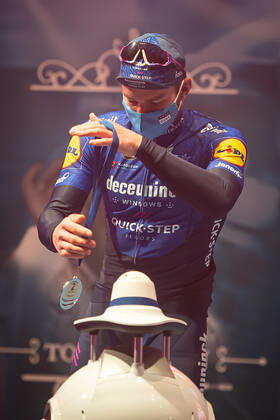 Radsport, E3 Harelbeke - Roboter führt Siegerehrung durch Zweiter - Florian Senechal (FRA - Deceuninck-Quick Step) bei der Siegerehrung - hier bei der Siegerzeremonie mit eigenstaendiger Uebernahme der Medaille von einem ferngesteuerten Roboter der die Ehrendamen Podiumsdamen Hostessen wegen der Covid-19 Corona Pandemie und der angemahnten Kontaktbeschraenkungen ersetzt - hier abgeschottet in der Sporthalle von Harelbeke ohne Zuschauer wegen der Covid-19 Corona Pandemie - Podium - Siegerehrung - Ehrung - Auszeichnung - Zeremonie - Zelebrierung - Ceremony - Jubel - Freude - Luck - Emotion - Emotionen - Mimik - Mimic - Gestik - Gestic - Hochformat hoch hochkant vertikal Event Veranstaltung: 64. E3 Saxo Bank Classic - Harelbeke nach to Harelbeke 203.9 km - Ort Location: Harelbeke - Region: West-Vlaanderen (Flandern) - Land Country: Belgien Belgium - Datum Date: 26.03.2021